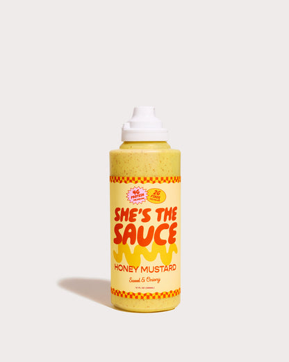 Bottle of She's the Sauce Honey Mustard on a light grey background
